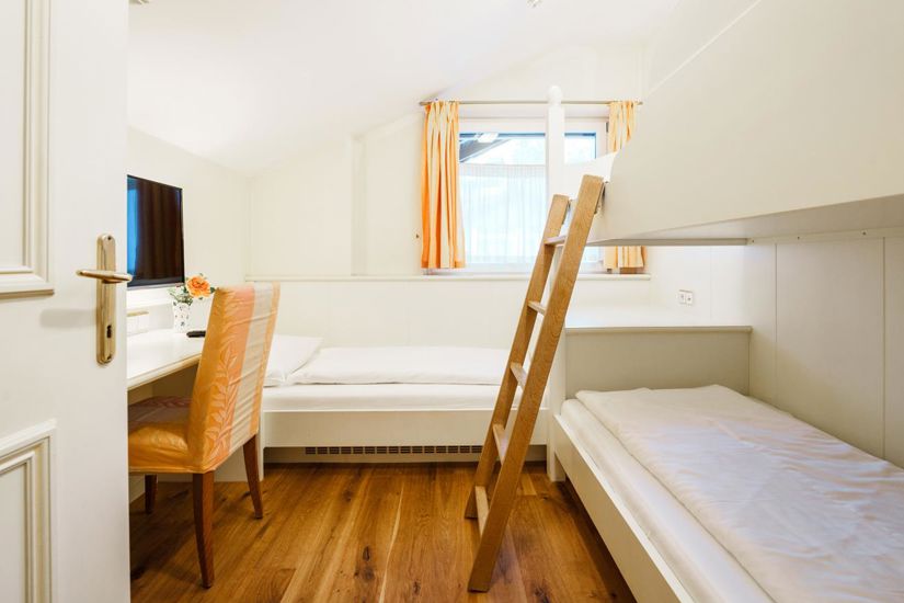 Das Kinderzimmer des Familienzimmers Ifinger mit Stockbett, Einzelbett und Fernseher